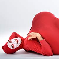 Red Bastard, bouffon-clown, lies in a pinup pose